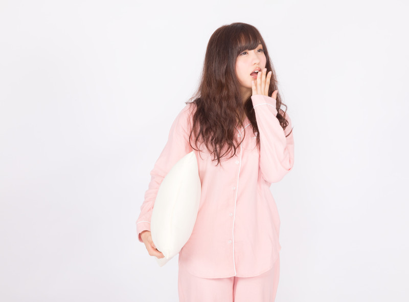 あくびをするピンクパジャマの女性の画像